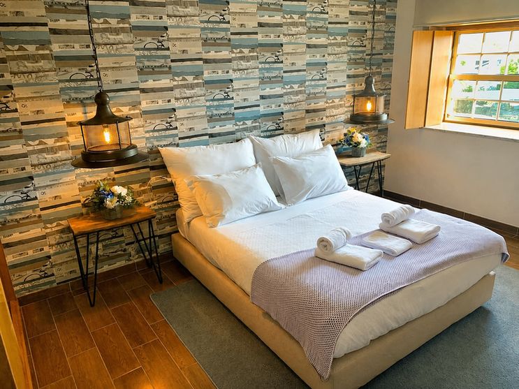 Um quarto duplo na Casa Aldeia da Lapa com roupa de cama branca e cabeceira de madeira